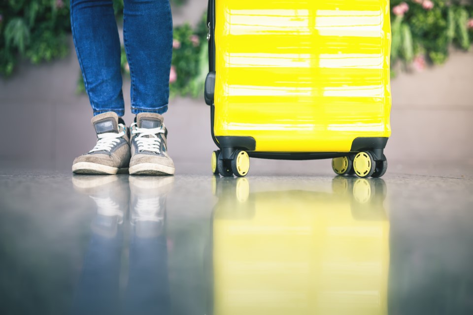 Valigia e gambe umane in secondo piano