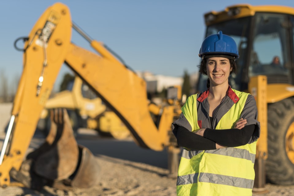 Lavoratrice con casco di sicurezza con una gru nello sfondo